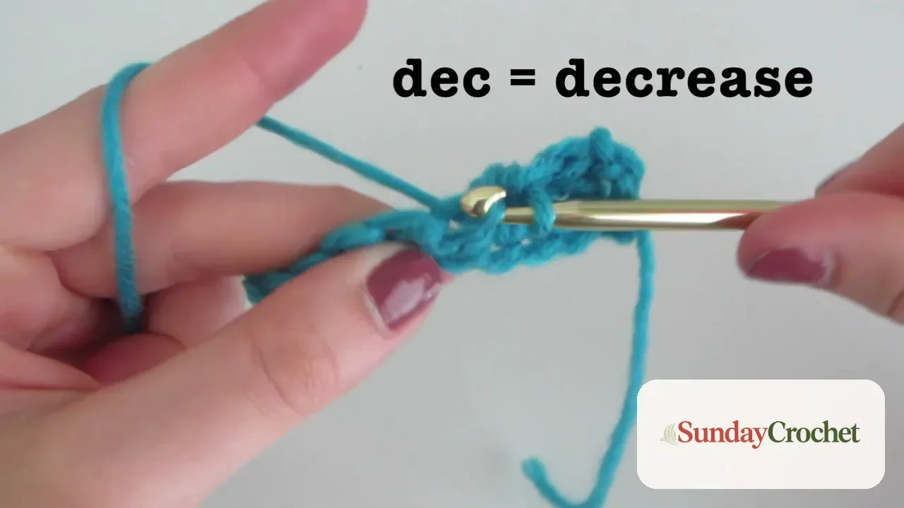 Hands and crochet hook working a decrease across blue stitches
