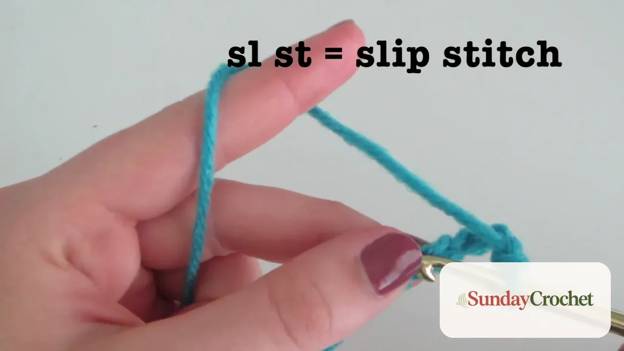 Close-up of hands using a crochet hook to make a slip stitch with blue yarn