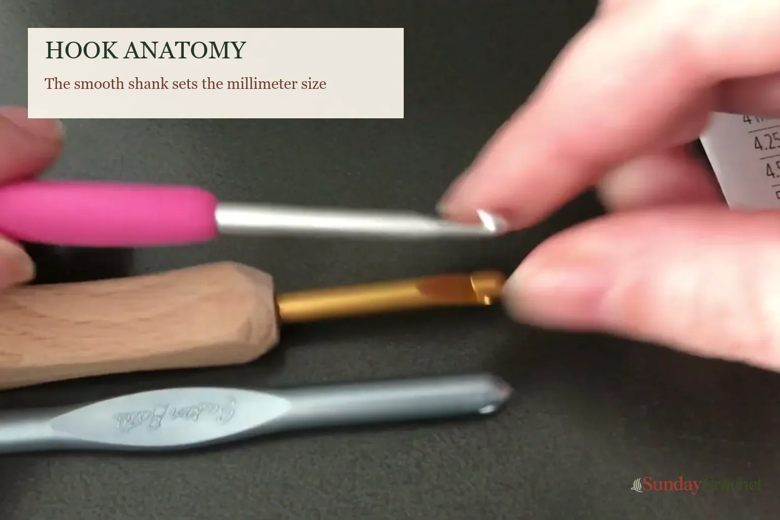 Hands comparing crochet hook shanks and throats to identify where hook size is measured