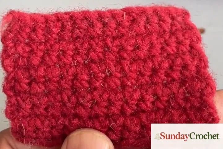 Muted red wool crochet swatch with a soft fuzzy halo around the stitches
