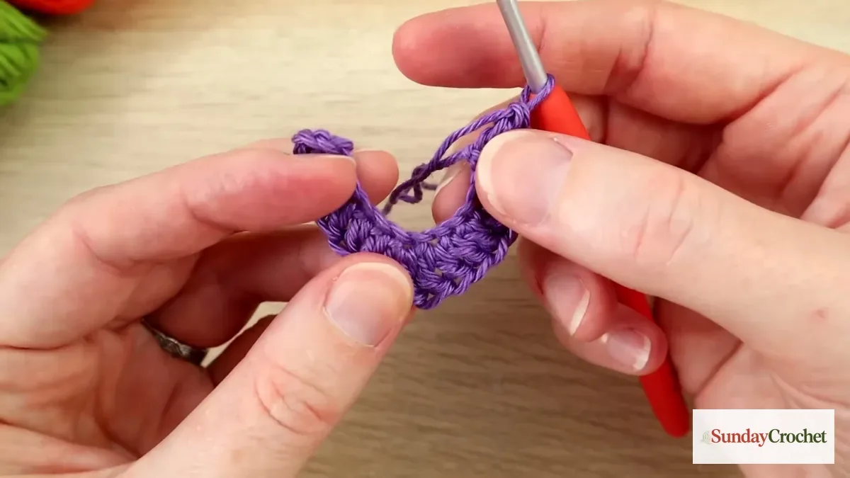 Hands work purple double crochet stitches along the bat applique foundation to form its curved first side
