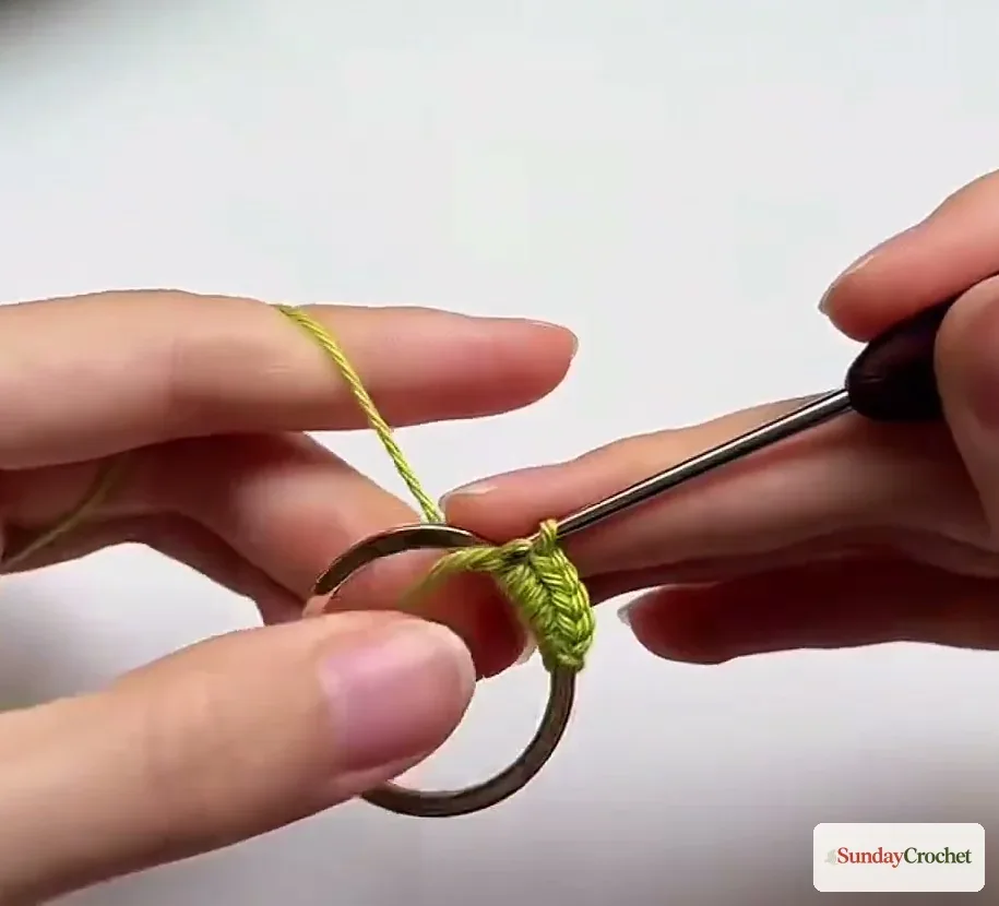 Hands crochet green single crochet stitches around the first metal ring of a mini bag
