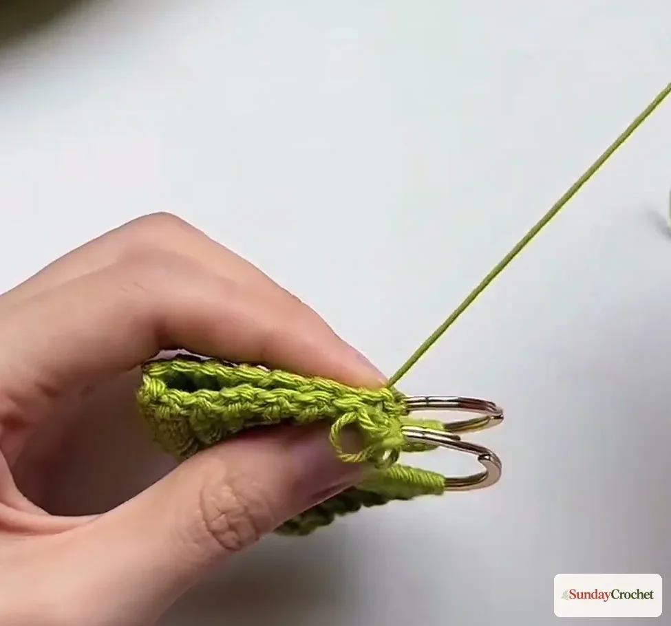 Folded mini bag held at the side edge as its two metal rings meet before seaming