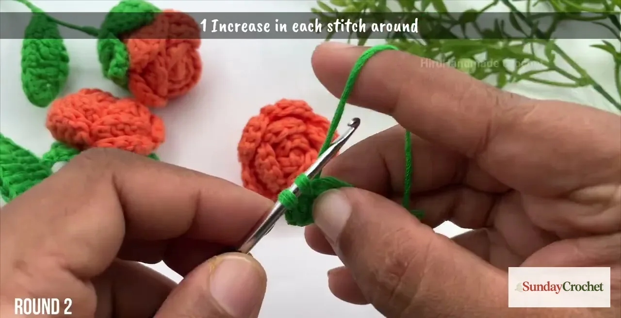 Green yarn is worked into the small crochet flower base during its increase round