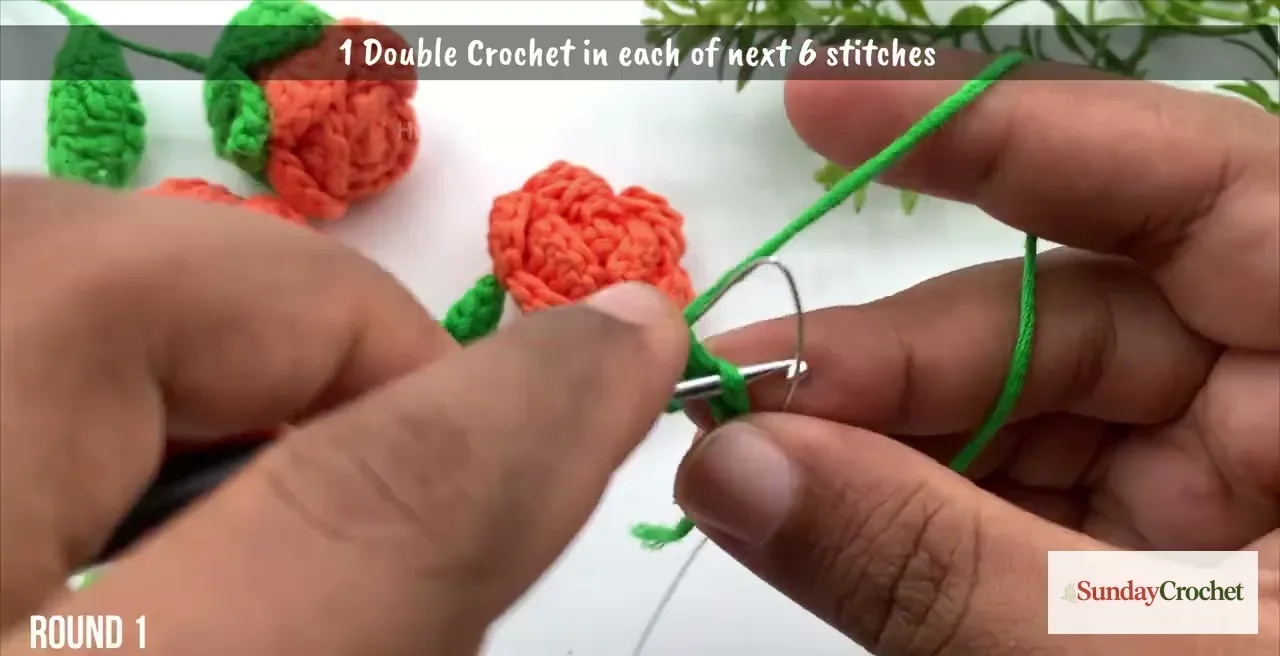 A green crochet leaf is shaped around a folded piece of floral wire