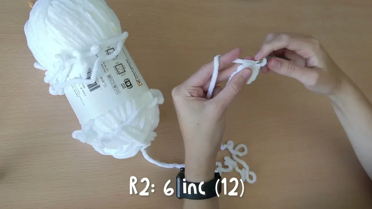 The second round of a white crochet bee wing is shaped with six increases to reach 12 stitches