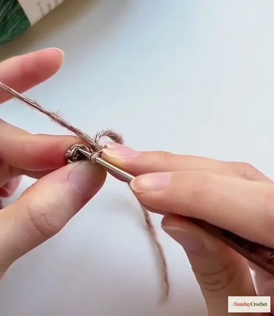 Hands crochet the small brown trunk as a narrow tube of single crochet stitches