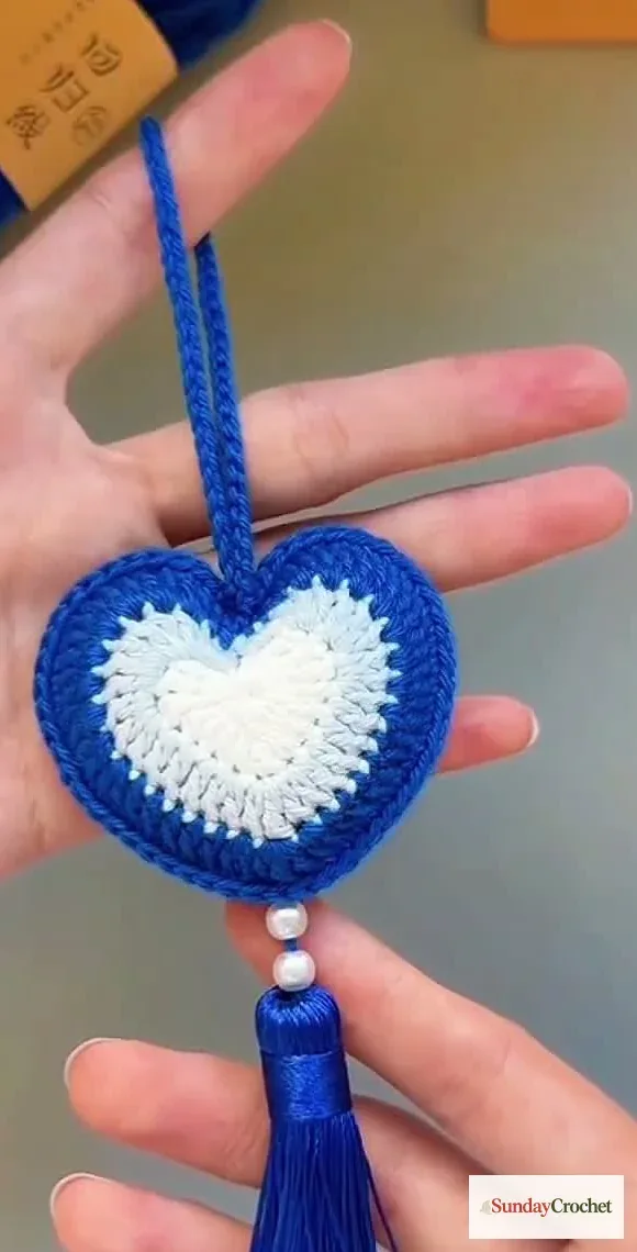 Finished blue-and-white crocheted heart displayed with a hanging loop, two beads, and a matching tassel
