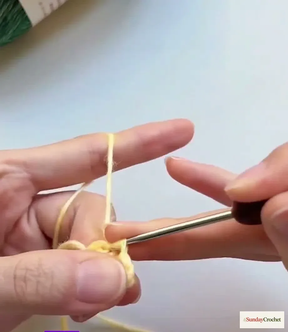 Hands shape a crocheted star point with chains and stitches on the hook