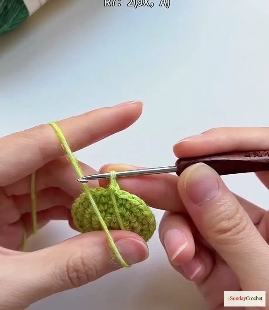 Hands draw out a long yarn loop while crocheting the tree's fluffy loop stitch