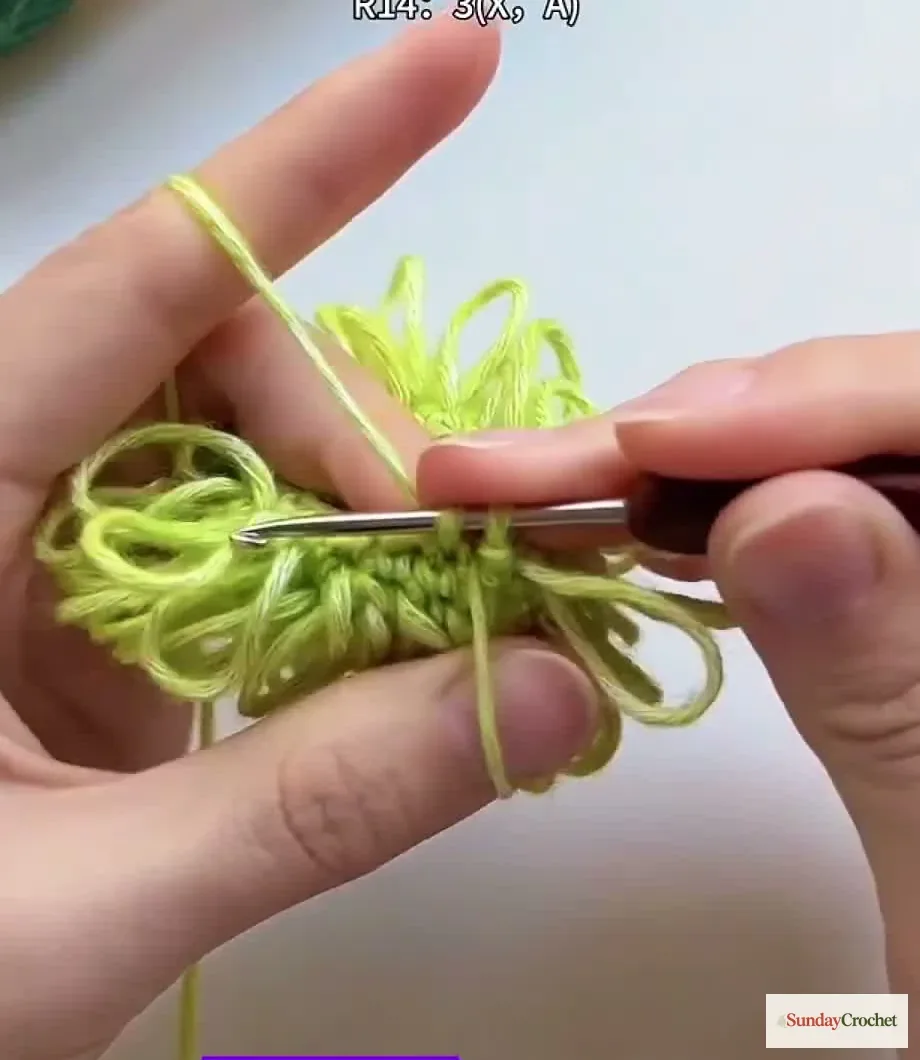 Hands crochet a decrease into the looped tree body to taper its shape