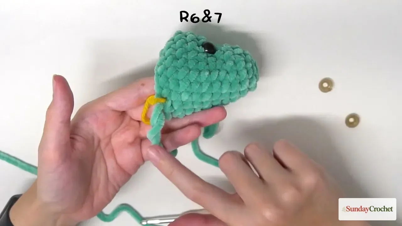 A glossy safety eye is positioned between Rounds 6 and 7 on the crocheted snake head