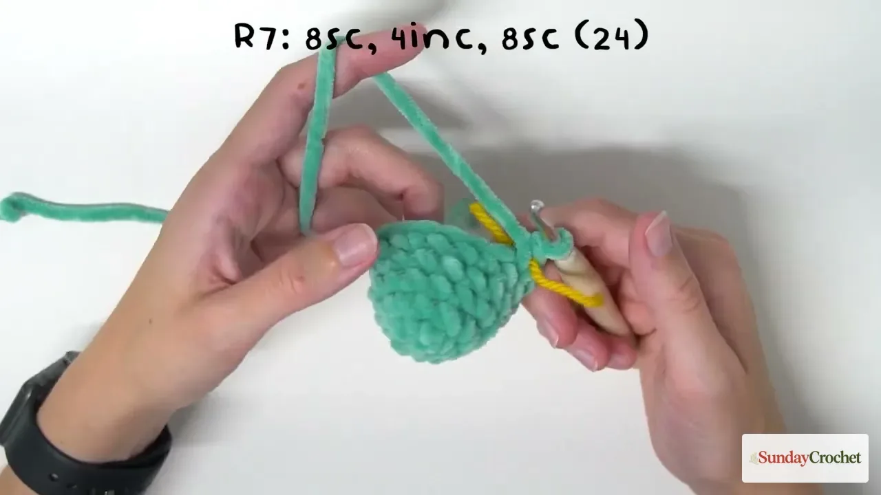 Hands crochet the mint-green snake head at Round 7, working eight single crochets, four increases, and eight single crochets