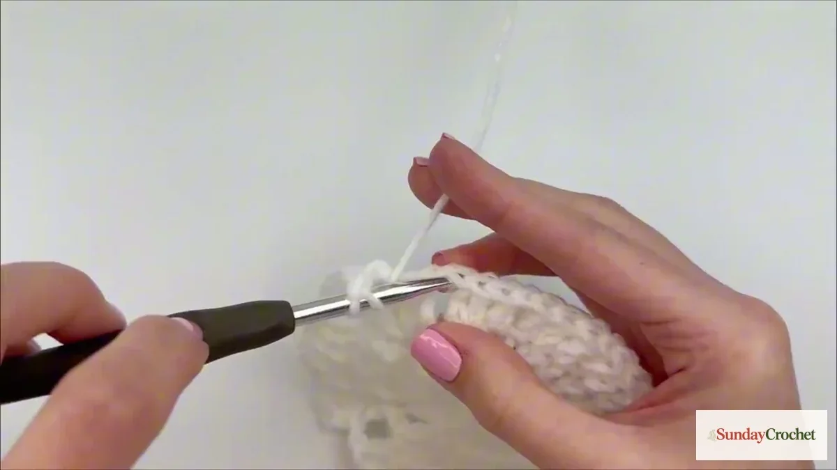 Left-handed crocheter works an ivory stitch into the round blanket center
