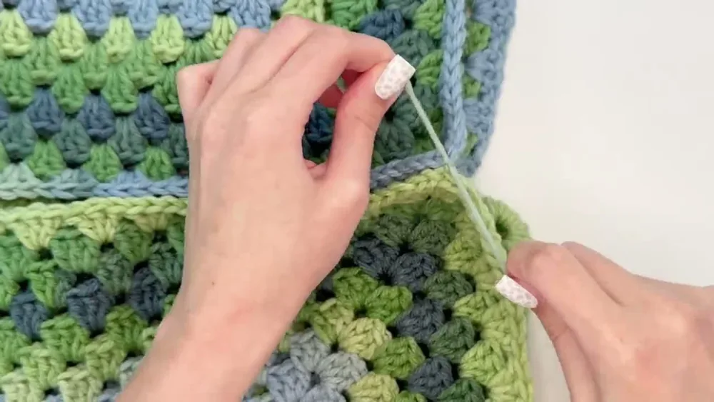 Two matching granny hexagons lie together as the center back seam is aligned for joining