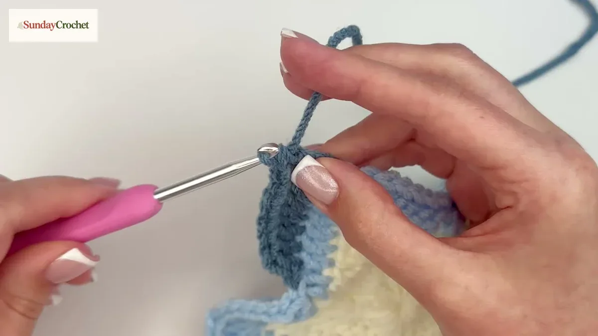 A new slate-blue yarn is joined at the start of a round on the star-shaped crochet panel