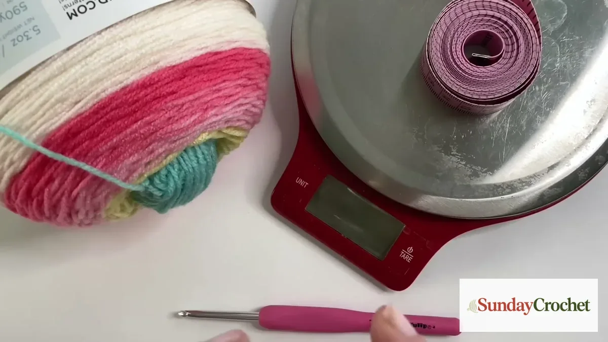 A multicolor yarn skein beside a digital scale, with a crochet hook on the table.