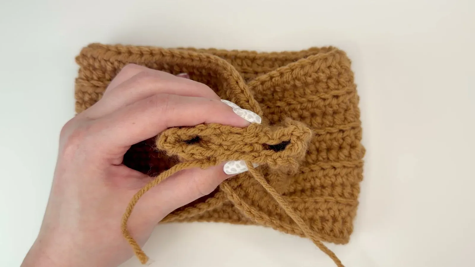Tapestry needle stitching through the folded layers at the center of a crochet headband