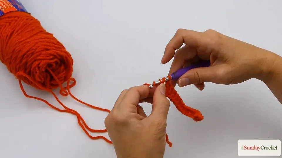 Hands making a tall triple crochet stitch with several loops on the hook