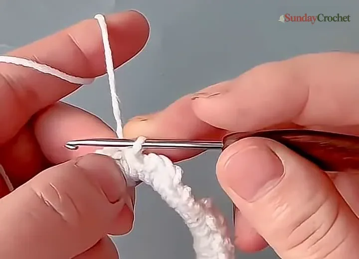 Hands work a double crochet into the white round covering the paired elastic hair ties