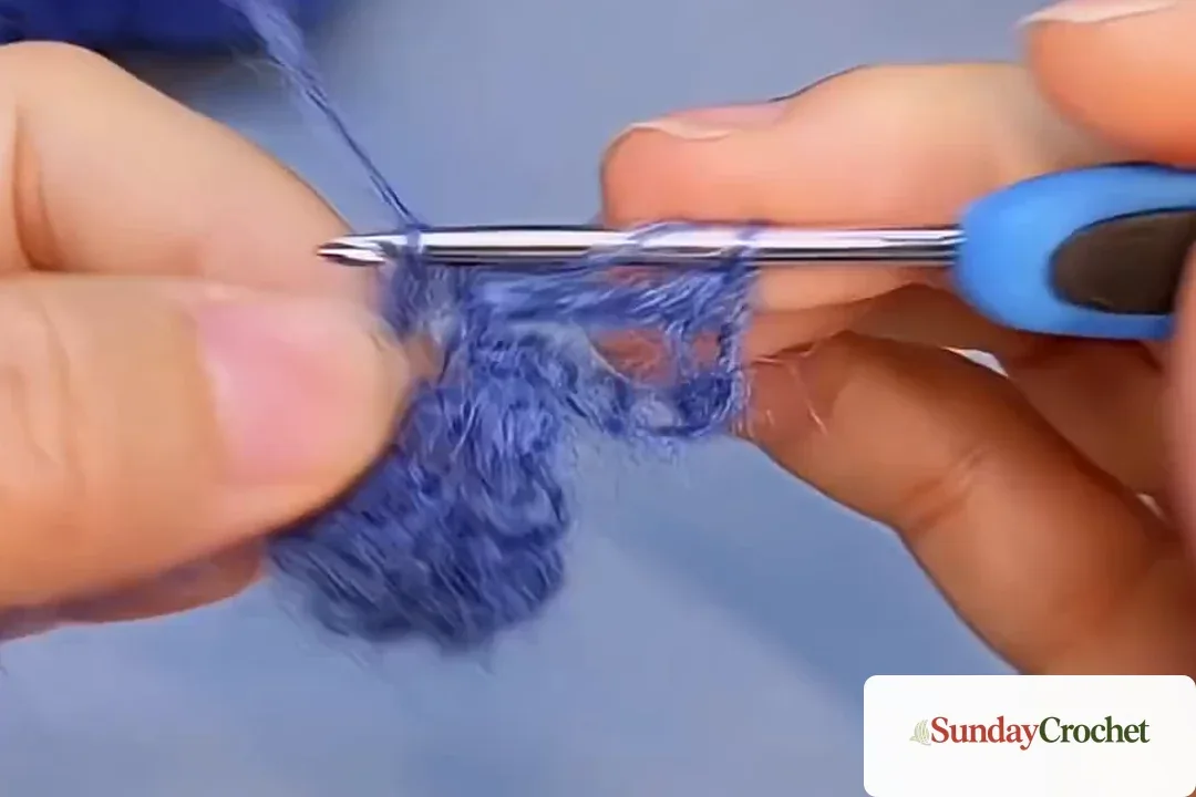 Blue yarn chain loop with double crochet stitches forming the next fan