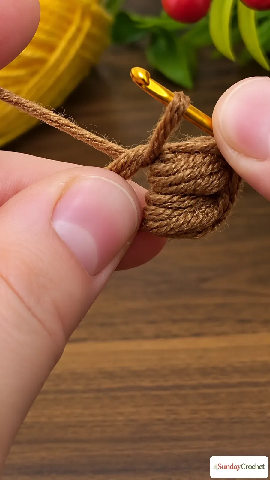 Hands use a hook and brown yarn to work the sunflower's compact circular center