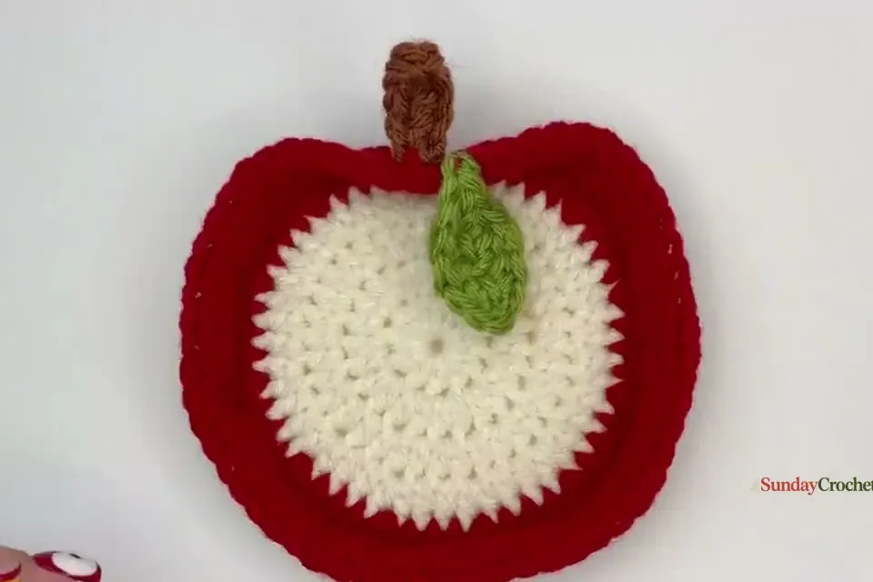 Completed red and cream apple trinket dish with its green leaf, brown stem, and embroidered seed details