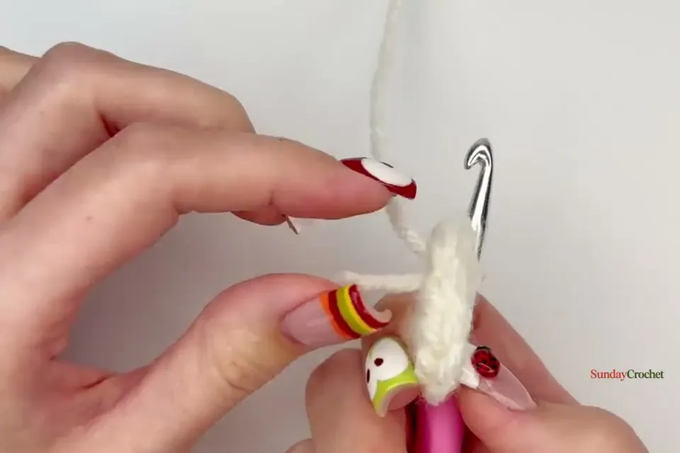 Hands work the first cream half double crochet stitches into a small faux magic ring