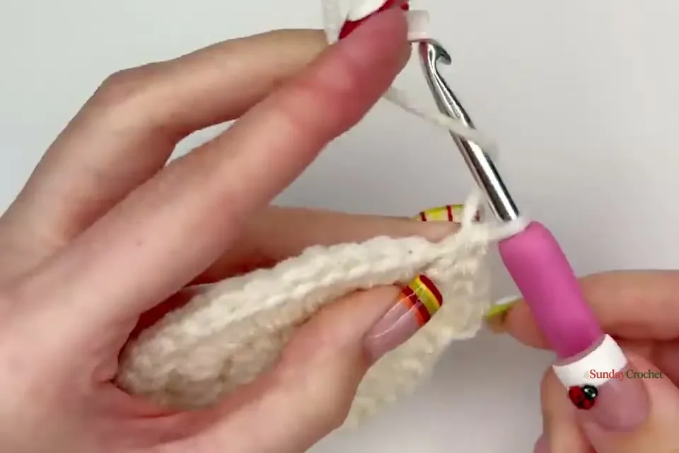 The cream center grows through its fourth joined round before the red yarn change