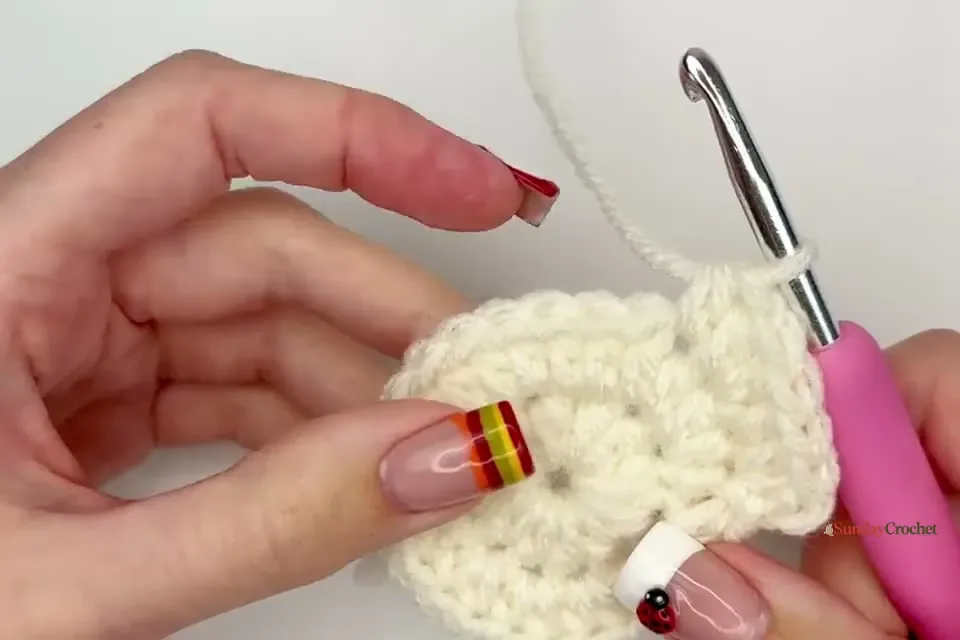 Hands continue the cream circle, placing an increase in every other stitch