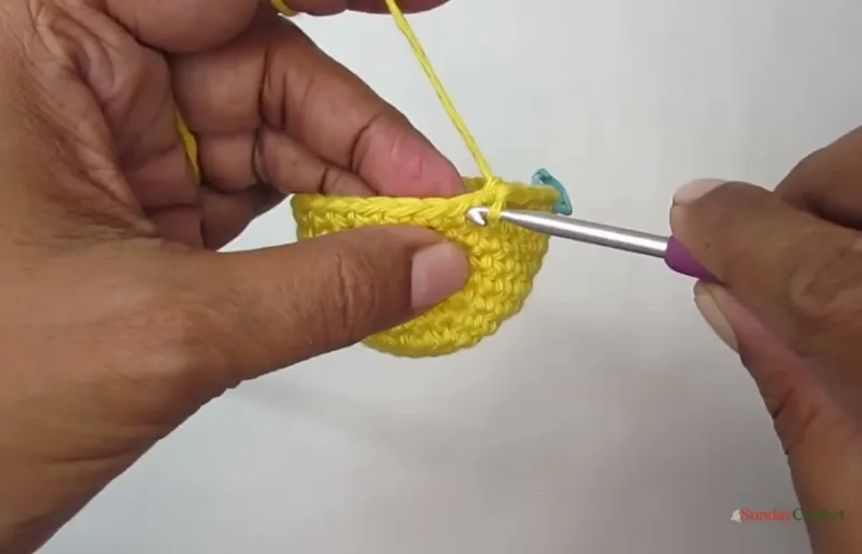 Hands crochet the yellow pumpkin body in continuous single crochet rounds with a stitch marker at the round start