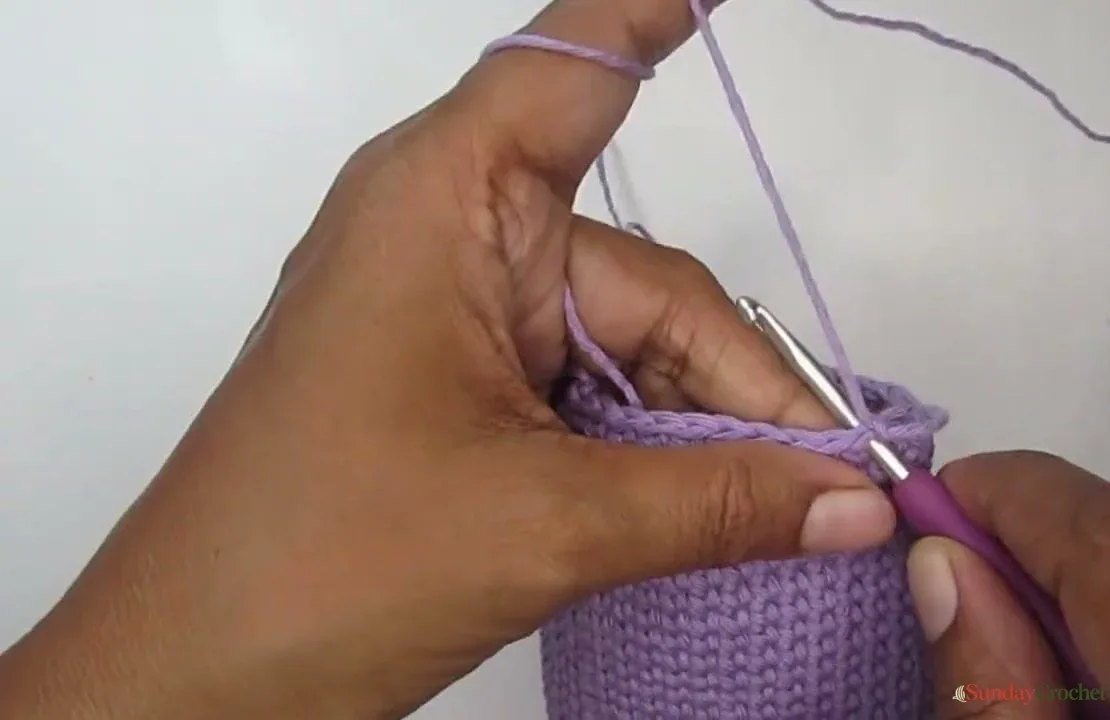 Hands begin a single-crochet flap along the top edge of the lavender pouch
