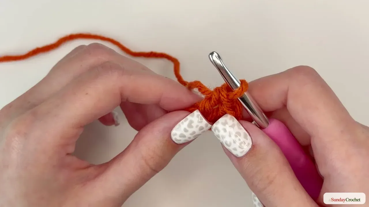 Crochet hook working into the orange round of the pumpkin granny-square center
