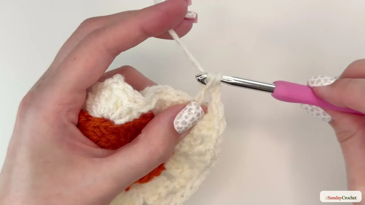 Forest-green yarn attached to the cream motif to begin the granny-square border