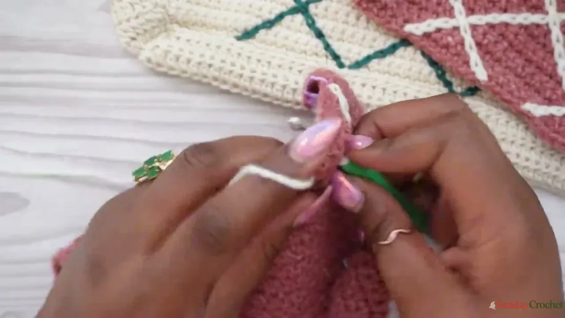 Hands add a contrasting surface slip stitch to the crochet lattice on a tote panel