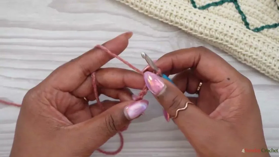 Hands begin a crochet tote panel by working the first stitches into a foundation chain