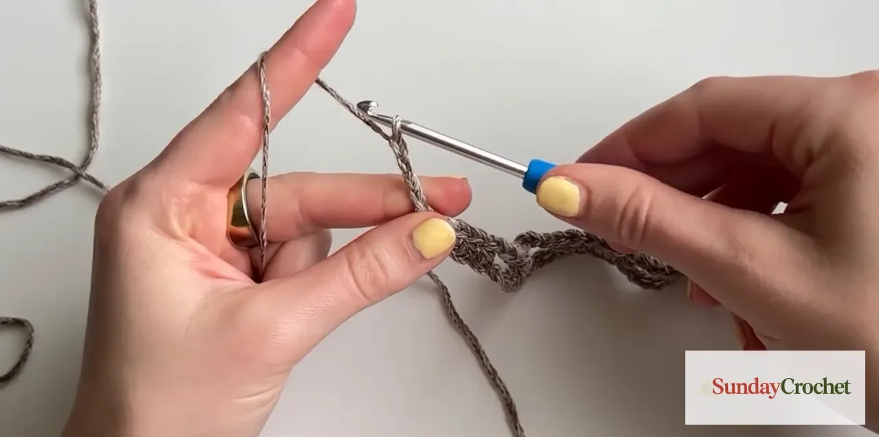The first treble-crochet row begins above the poncho mesh foundation
