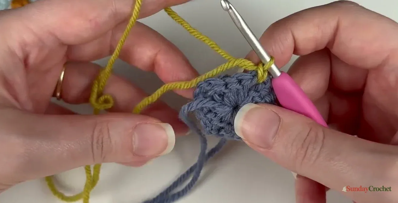 The new yarn tail lies over the hook so the first chain catches it during a color change