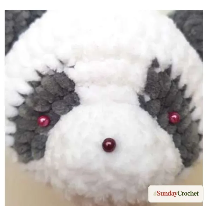 Safety eyes and nose pinned symmetrically on the panda face before fastening