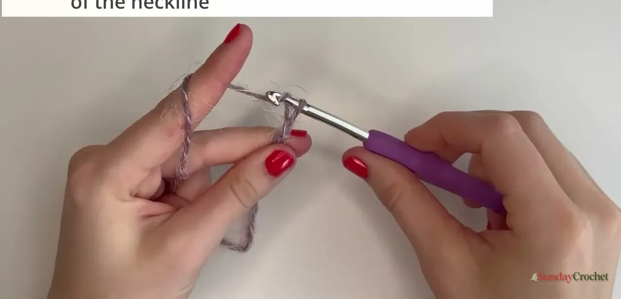 Hands use a crochet hook to work the foundation chain of a fuzzy raglan sweater