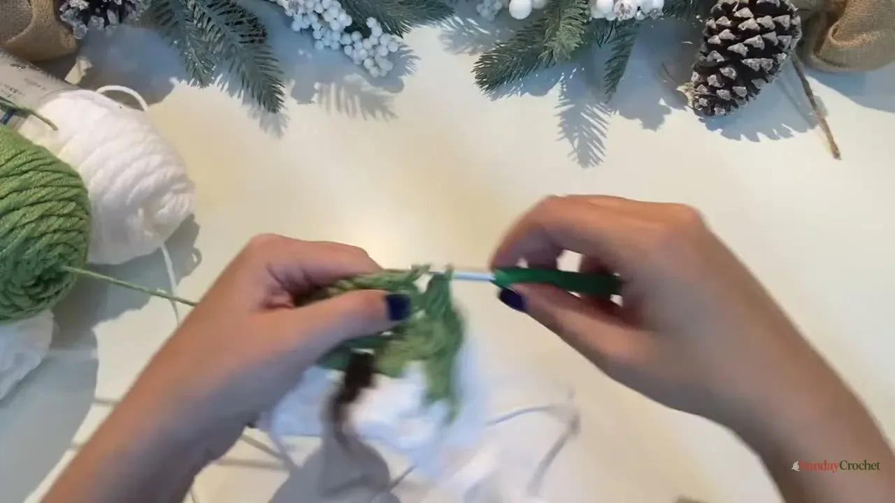 Hands work green granny clusters over the white background to shape the Christmas tree
