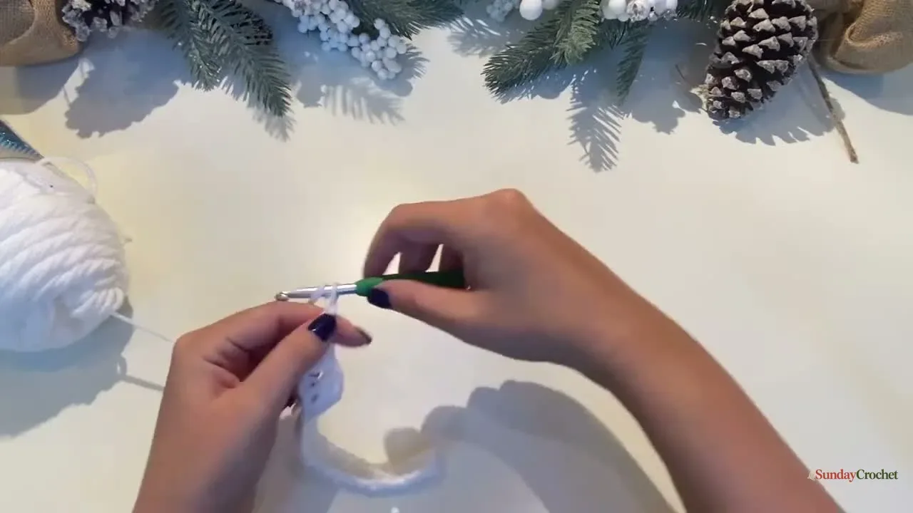 Hands crochet the first white row of three-double-crochet granny clusters