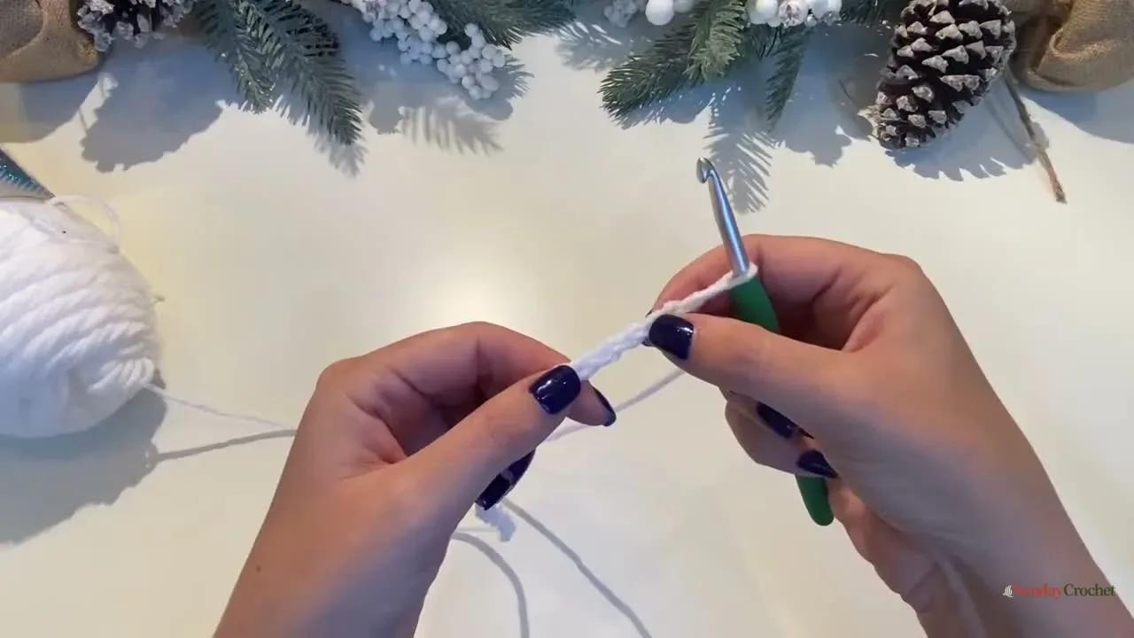 Hands make the white foundation chain for a Christmas tree granny-stitch square
