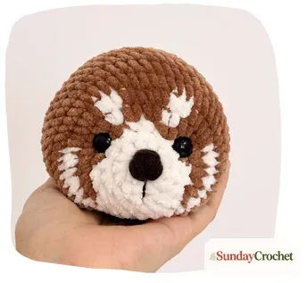 Red panda head in progress with cream and brown colorwork around the eyes