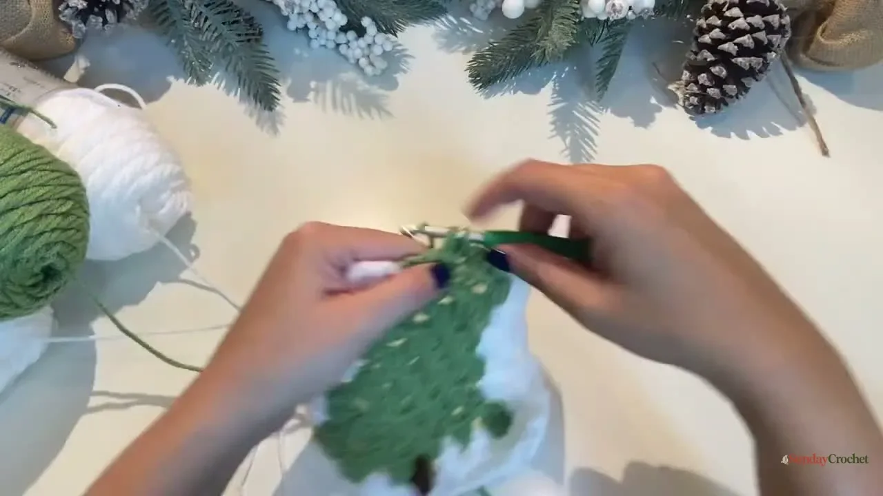 Hands add cream granny clusters around the narrowing green tree motif